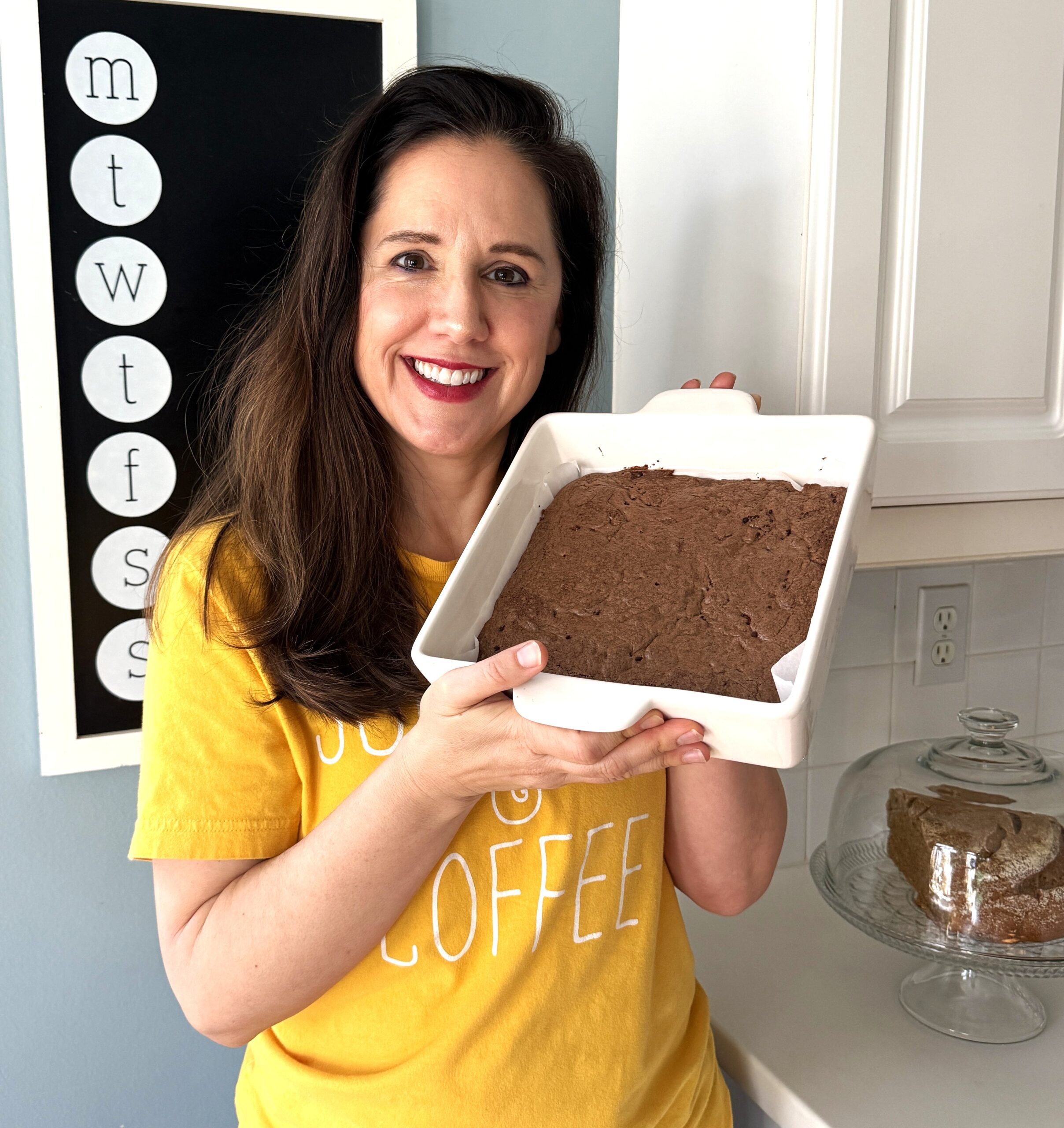 Woman holding a pan of fresh milled einkorn brownies with rich cacao whole grain brownie close-up in background