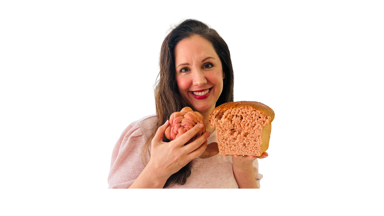 Woman holding pink bread roll next to a rose-shaped pink bread made with fresh milled flour and beet powder