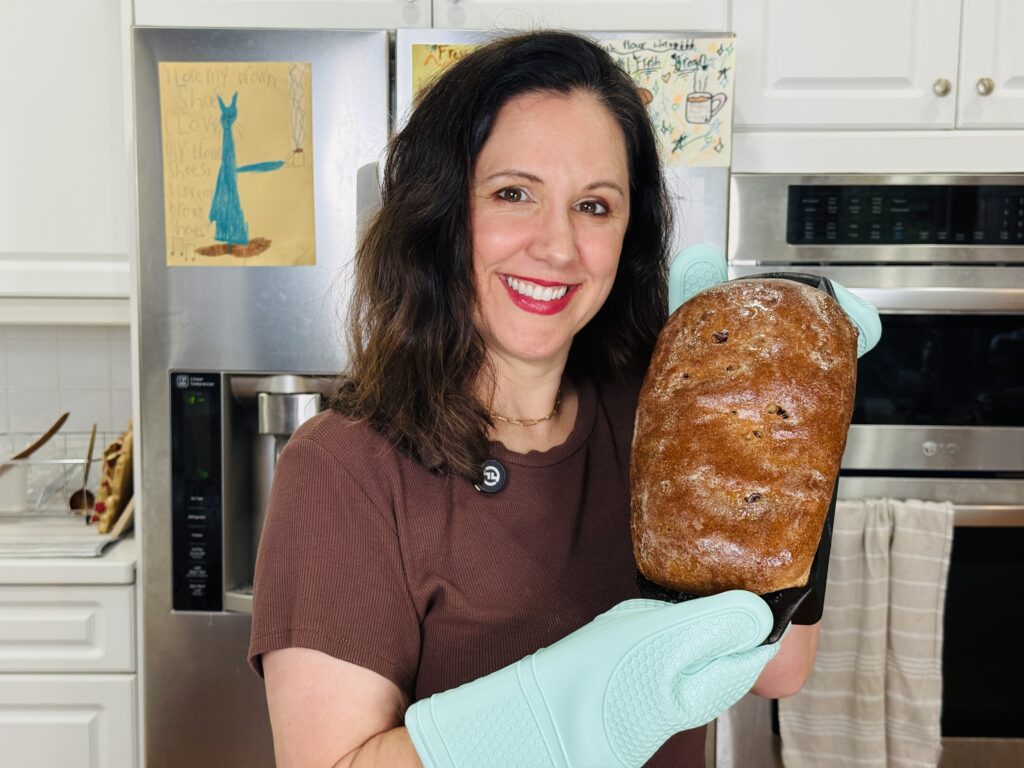 Woman holding a loaf of soft chocolate sandwich bread made with fresh milled hard white wheat flour
