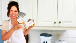 Woman holding homemade drop biscuits in a mason jar and gift bag with easy DIY biscuit gifts made with fresh milled flour