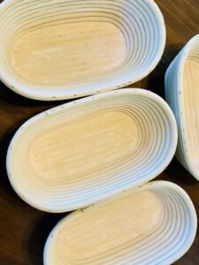 Several oval rattan banneton baskets lightly dusted with flour, stacked together