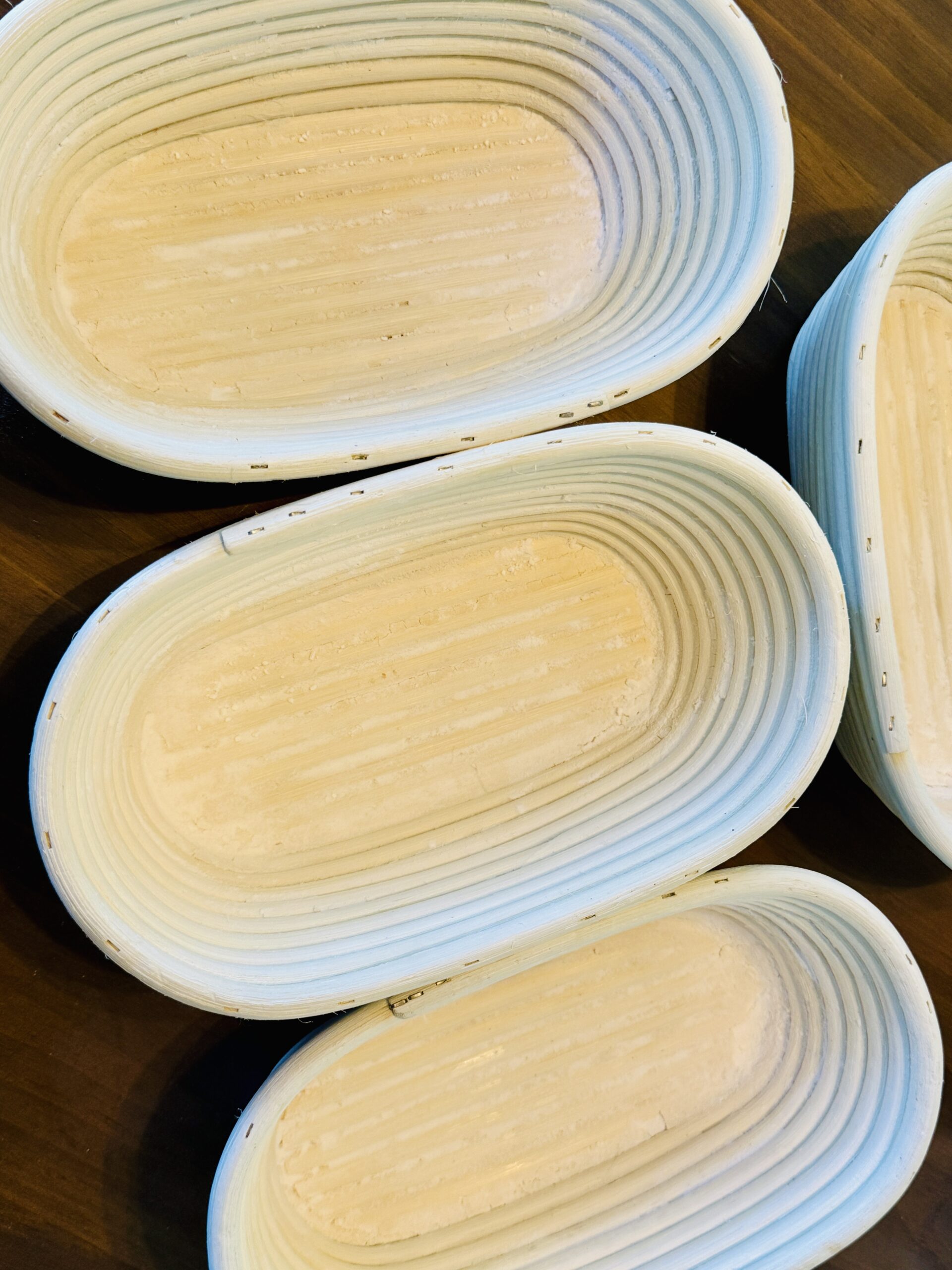 Several oval rattan banneton baskets lightly dusted with flour, stacked together