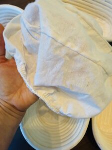 Hand holding a linen banneton liner cloth used to prevent dough from sticking
