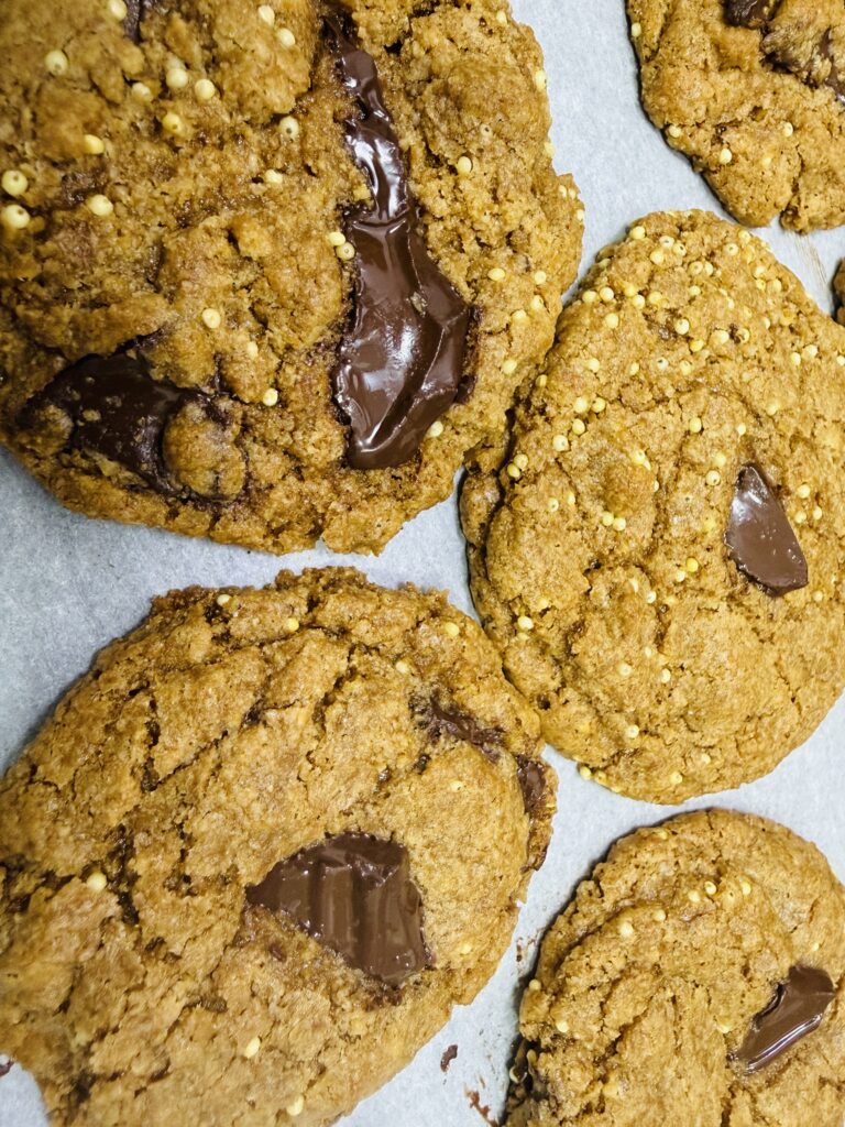 Fresh milled spelt chocolate chip cookies on a parchment lined baking sheet fresh from the oven