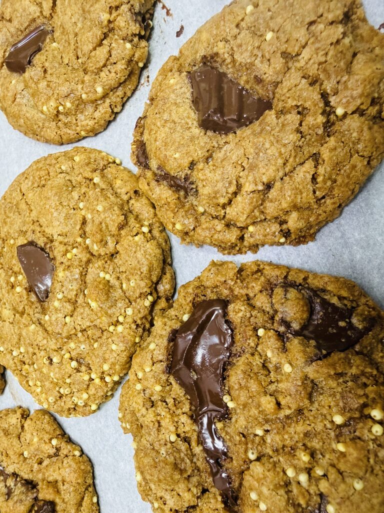 Fresh milled spelt chocolate chip cookies on a parchment lined baking sheet fresh from the oven