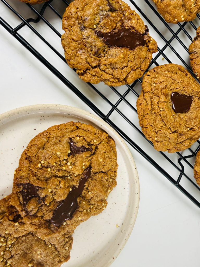 Overhead view of fresh milled spelt chocolate chip cookies made with a chopped semi-sweet chocolate bar with cookies on a plate beside it.